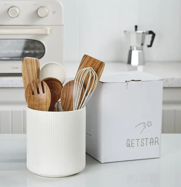 Ribbed white Getstar utensil holder with wooden spoons and a whisk beside a Getstar gift box on a kitchen counter